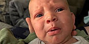 Honest is registered to the contest to win money with this photo: baby, infant, face, expression, confused, worry, onesie, clothing, mittens, hand, person, indoor, couch, blanket, soft, closeup, portrait, newborn, skin, head