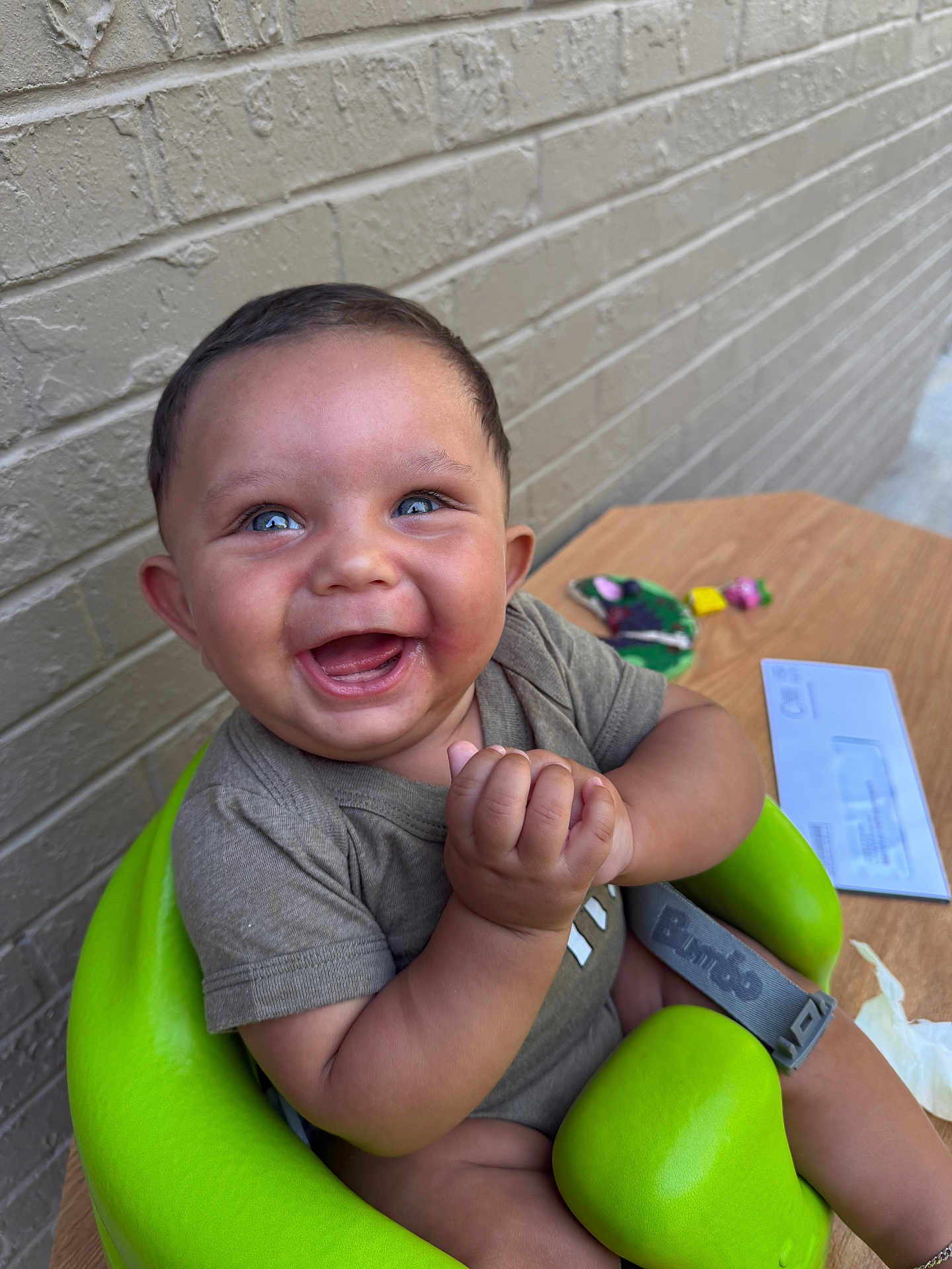 Deangelo joined the competition — help win amazing prizes! baby, child, smiling, happy, blue_eyes, green_seat, clapping_hands, short_sleeve_shirt, brick_wall, wooden_table, toys, letter, indoor, person, infant, cute, seat, joyful, portrait, clothing