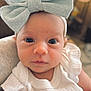 baby, child, infant, headband, bow, white_clothing, strawberry_patch, closeup, portrait, face, eyes, cute, soft_light, indoors, blurred_background, person, newborn, gaze, holding, small_hand