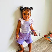 Hosana participe au concours pour gagner de l'argent avec cette photo : barefoot, casual_clothing, child, cute, girl, home, indoor, person, pigtails, playroom, portrait, purple_shorts, smartphone_case, standing, striped_shirt, toddler, toy, white_wall, wood_floor, young_child