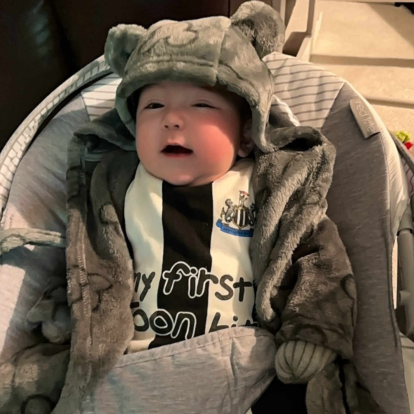 Cole is registered to the contest to win money with this photo: baby, bonnet, cap, clothing, coat, couch, face, furniture, glove, hat, head, hood, hoodie, jacket, knitwear, person, photography, portrait, sweater, sweatshirt