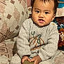 Viona is registered to the contest to win money with this photo: child, couch, cozy, curious, cushion, cute, expression, face, hands, home, indoor, knitted, patterned, person, portrait, seated, sweater, tape, toddler, young_child