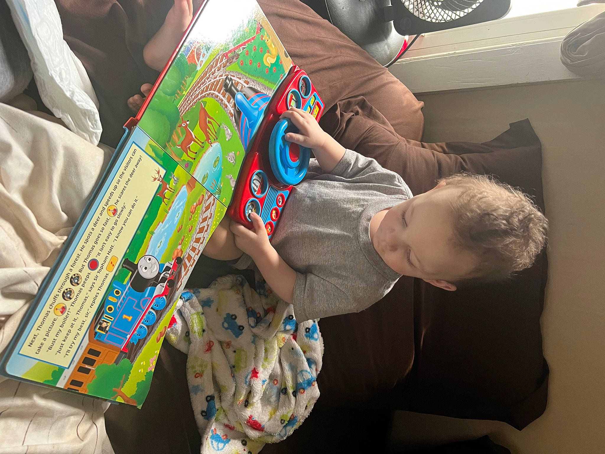 Amir is registered to the contest to win money with this photo: art, baby, child, comfort, fun, learning, mechanical_fan, pattern, person, plastic, play, publication, reading, room, sitting, toddler, toy, travel, visual_arts