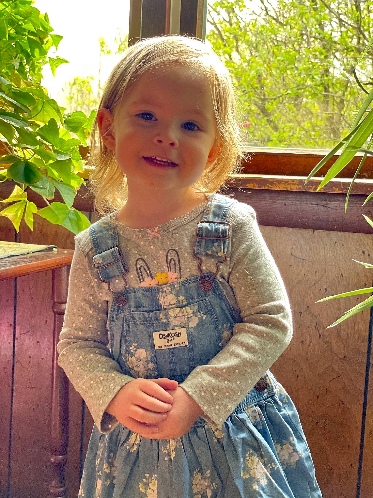 Amity is registered to the contest to win money with this photo: baby_toddler_clothing, cheek, day_dress, dress, eye, facial_expression, green, hair, hairstyle, happy, iris, joy, leaf, person, plant, skin, sleeve, smile, standing, sunlight