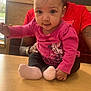 Emriella is registered to the contest to win money with this photo: baby, child, person, indoor, table, pink_clothing, minnie_mouse, socks, curious, adult, supporting_hand, window, daylight, wooden_table, red_shirt, tattoo, casual, seated, closeup, smiling