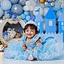 baby, child, dress, blue_dress, tiara, birthday, one_year_old, smile, balloons, castle, decorations, fairy_lights, celebration, happy, portrait, floor, festive, cute, young_child, indoor