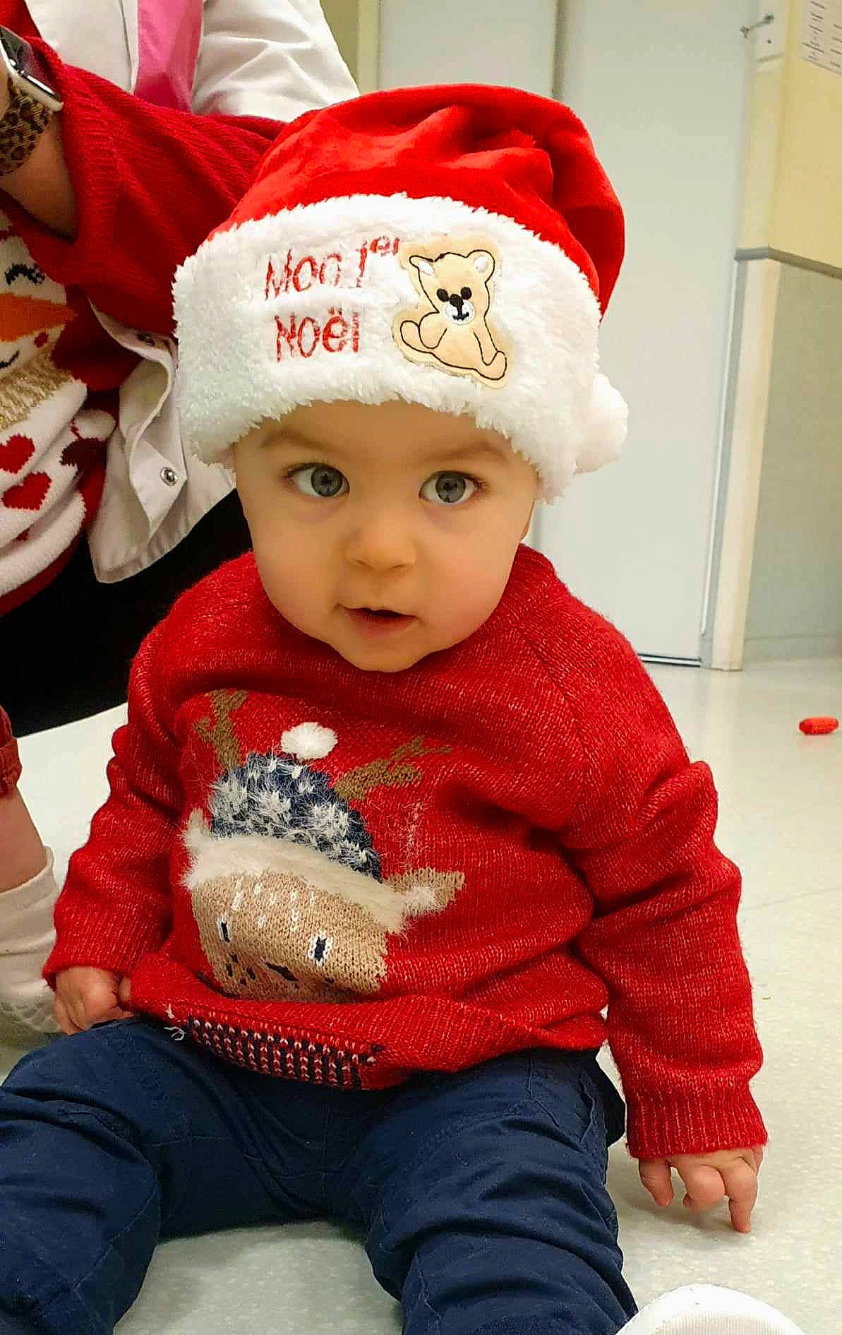 Diego participe au concours pour gagner de l'argent avec cette photo : baby, baby_toddler_clothing, cap, cheek, child, clothing, costume_hat, event, facial_expression, fashion_accessory, headgear, headwear, holiday, knit_cap, pattern, person, red, sitting, skin, sleeve