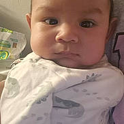 Steven joined the competition — help win amazing prizes! baby, infant, child, portrait, close_up, face, serious, indoors, blanket, dinosaur_pattern, clothing, pillow, couch, seated, looking_at_camera, brown_hair, eyes, home, cozy, photography