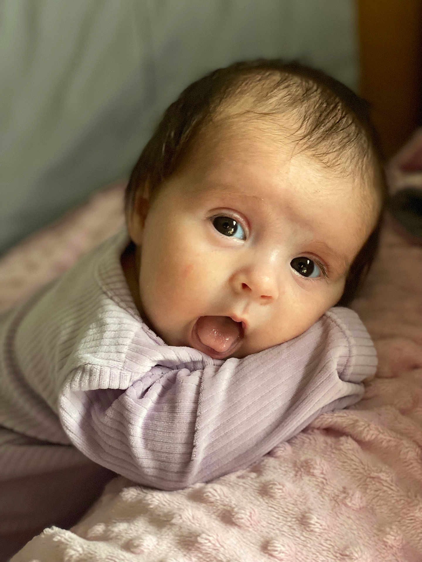 Rhiannon is registered to the contest to win money with this photo: baby, infant, face, eyes, tongue, blanket, soft_texture, clothing, purple, cute, resting, closeup, child, young, portrait, skin, head, expression, indoors, cozy