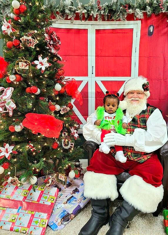 Ryleigh joined the competition — help win amazing prizes! christmas, christmas_decoration, christmas_eve, christmas_ornament, christmas_tree, event, evergreen, green, hat, headwear, holiday, holiday_ornament, joy, lap, ornament, person, plant, red, santa_claus, smile