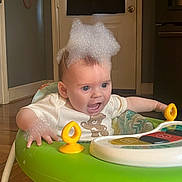 Raven joined the competition — help win amazing prizes! baby, infant, walker, foam, bubbles, surprised_expression, blue_eyes, toy, playtime, plastic, green, onesie, clothing, home_interior, door, hardwood_floor, hand, sitting, smile, cute