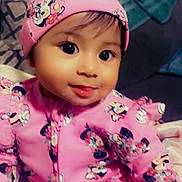 Enveeluna is registered to the contest to win money with this photo: apparel, baby, blanket, cartoon_character, child, couch, cozy, cute, face, happy, hat, hoodie, indoor, pattern, person, pink_clothing, portrait, sitting, smile, young_child