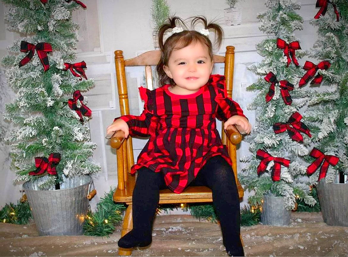 Anastacia joined the competition — help win amazing prizes! christmas_decoration, christmas_ornament, christmas_tree, dress, eye, facial_expression, flowerpot, happy, head, houseplant, human_body, joy, outerwear, person, plant, red, sleeve, smile, standing, toddler