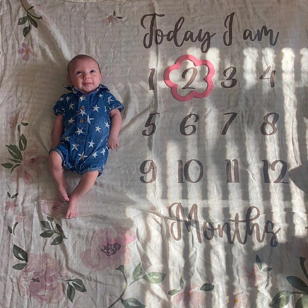 Renesmee is registered to the contest to win money with this photo: baby, bed, blanket, clothing, cushion, dress, face, furniture, head, homedecor, newborn, pants, person, photography, portrait, quilt, sitting, t_shirt, text, wood