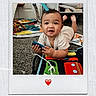 baby, child, toy, play_mat, floor, indoor, curious, happy, polaroid_frame, heart_emoji, carpet, colorful, tummy_time, hands, feet, smiling, person, room, furniture, playtime
