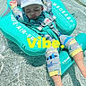 baby, child, swimming_pool, floatation_device, sleeping, water, swimwear, hat, safety_harness, relaxation, sun_protection, infant, blue, yellow, text_overlay, outdoor, summer, cute, peaceful, resting