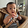 baby, high_chair, child, striped_shirt, indoor, face, hand, expression, mirror, reflection, furniture, table, plant, home, seat, curious, person, young_child, closeup, feeding