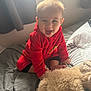 Louie is registered to the contest to win money with this photo: baby, child, red_fleece, stuffed_animal, bed, blanket, window, sunlight, indoor, smiling, happy, cute, plush_toy, person, soft_toys, curtains, cozy, infant, playful, casual