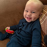 Louie joined the competition — help win amazing prizes! baby, smiling, toy, couch, blue_clothing, infant, happy, child, indoor, person, plush, seat, cute, young_child, relaxed, head, face, hand, sitting, cozy