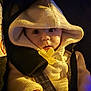 baby, hoodie, knitwear, pacifier, child, closeup, face, infant, warm_light, buttoned_clothing, seatbelt, car_seat, cute, young_child, indoors, portrait, expression, soft_texture, hand, cozy