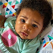 Bremi joined the competition — help win amazing prizes! baby, infant, child, curly_hair, face, eyes, expression, mint_green_shirt, donut_graphic, colorful_blanket, patterned_blanket, close_up, lying_down, cute, adorable, skin, earrings, soft_lighting, indoors, portrait