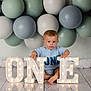 baby, child, first_birthday, balloons, illuminated_letters, one, floor, blue_clothing, sitting, celebration, portrait, indoor, decorations, cute, smiling, light, reflection, young_child, happy, party