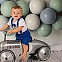 toddler, child, toy_car, blue_suspender, white_tshirt, balloons, pastel_colors, indoor, flooring, barefoot, steering_wheel, portrait, cute, happy, smiling, blonde_hair, blue_eyes, playful, background, studio