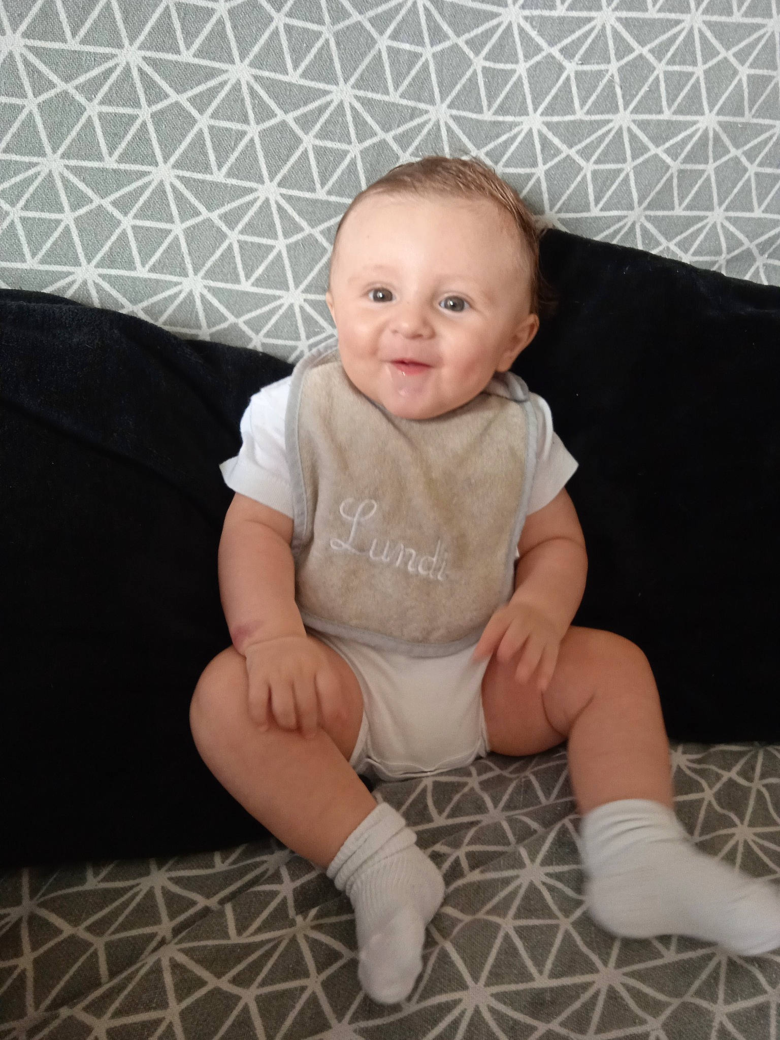Soann participe au concours pour gagner de l'argent avec cette photo : baby, baby_toddler_clothing, child, comfort, couch, face, flash_photography, floor, flooring, foot, human_leg, knee, leg, person, sitting, skin, sleeve, smile, sock, thigh