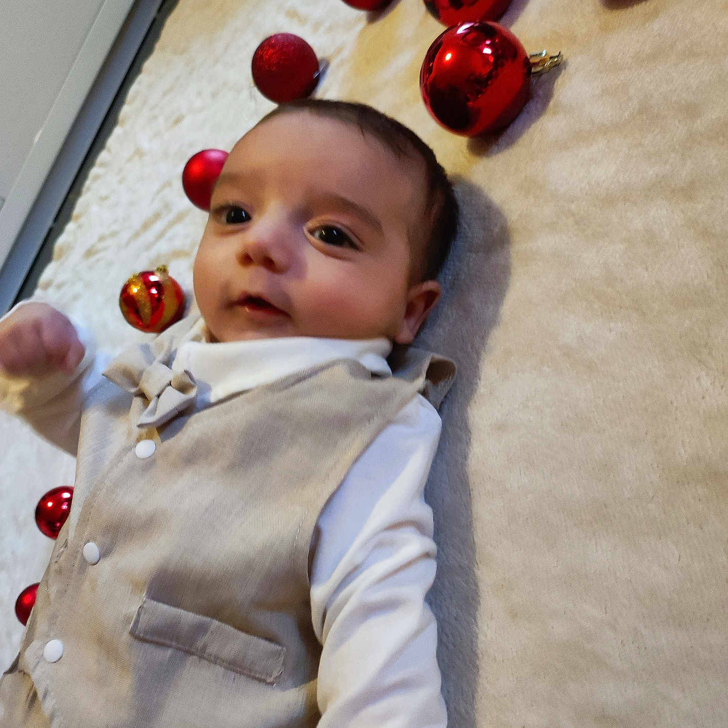 Raphaël a rejoint le concours — aidez-le/la à gagner de superbes lots ! baby, blanket, celebration, child, christmas_decor, cute, face, festive, holiday, holiday_decor, indoor, infant, laying_down, portrait, red_ornaments, smile, soft_texture, vest, white_shirt, young_child