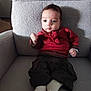 Raphaël a rejoint le concours — aidez-le/la à gagner de superbes lots ! baby, child, infant, sitting, armchair, clothing, red_sweater, pants, socks, indoors, cozy, cute, young, person, furniture, portrait, face, hands, feet, home