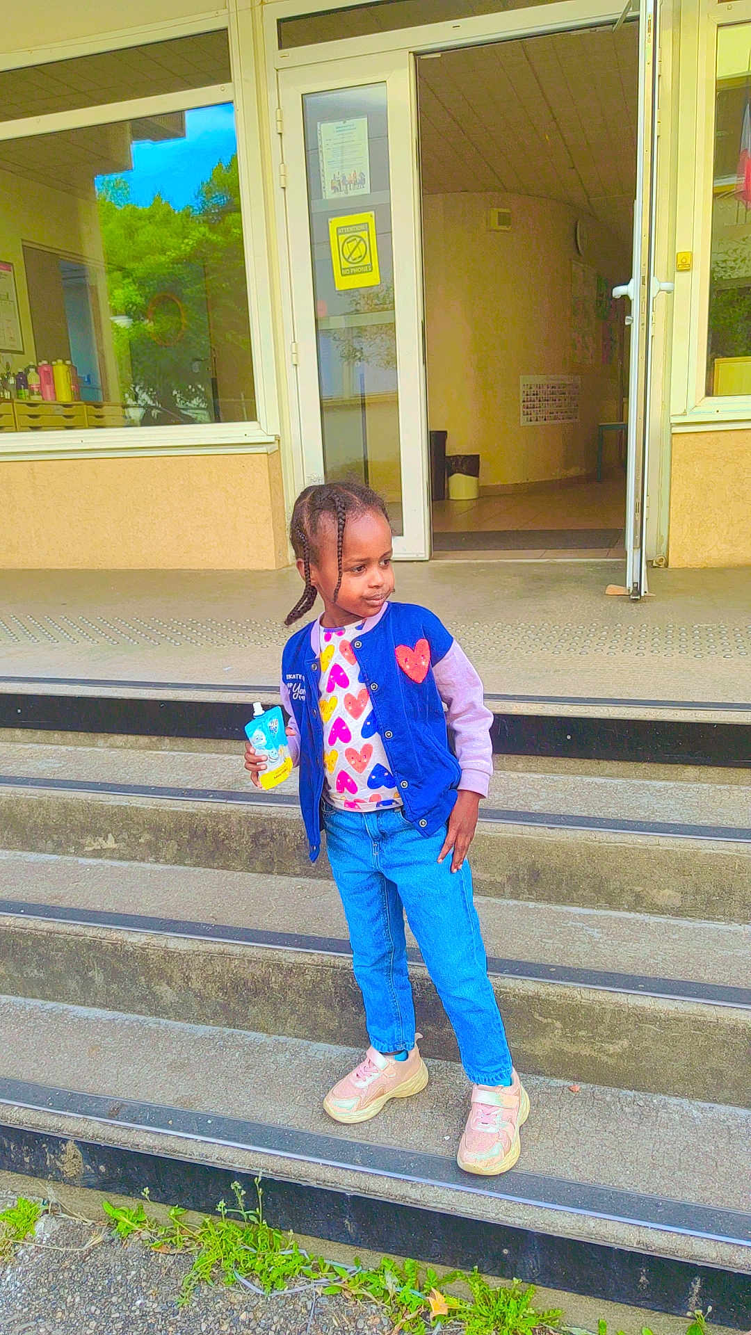 Bara'A a rejoint le concours — aidez-le/la à gagner de superbes lots ! child, steps, building, door, glass, reflection, drink_pouch, blue_jacket, heart_pattern, jeans, sneakers, outdoor, concrete, person, standing, casual_clothing, urban, daylight, hair_braids, confident_pose
