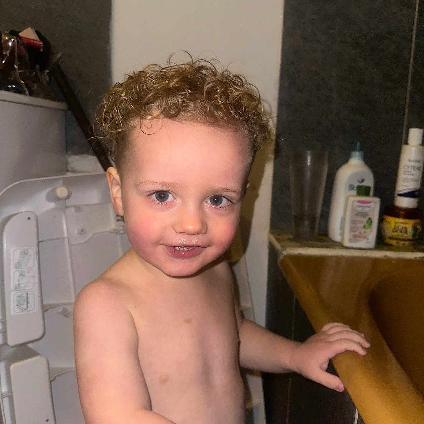 Aaron a rejoint le concours — aidez-le/la à gagner de superbes lots ! arm, bathroom, bathtub, child, curly_hair, expression, face, head, high_chair, holding, indoor, person, playful, skin, smile, standing, toddler, toiletries, wristband, young_child