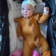 Elizabeth is registered to the contest to win money with this photo: baby, infant, child, stroller, portrait, headband, flower, onesie, brown_clothing, blanket, pink_blanket, cozy, lying_down, waving, smiling, wide_eyes, indoors, baby_fashion, plush_fabric, closeup