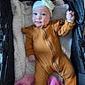 baby, infant, child, stroller, portrait, headband, flower, onesie, brown_clothing, blanket, pink_blanket, cozy, lying_down, waving, smiling, wide_eyes, indoors, baby_fashion, plush_fabric, closeup