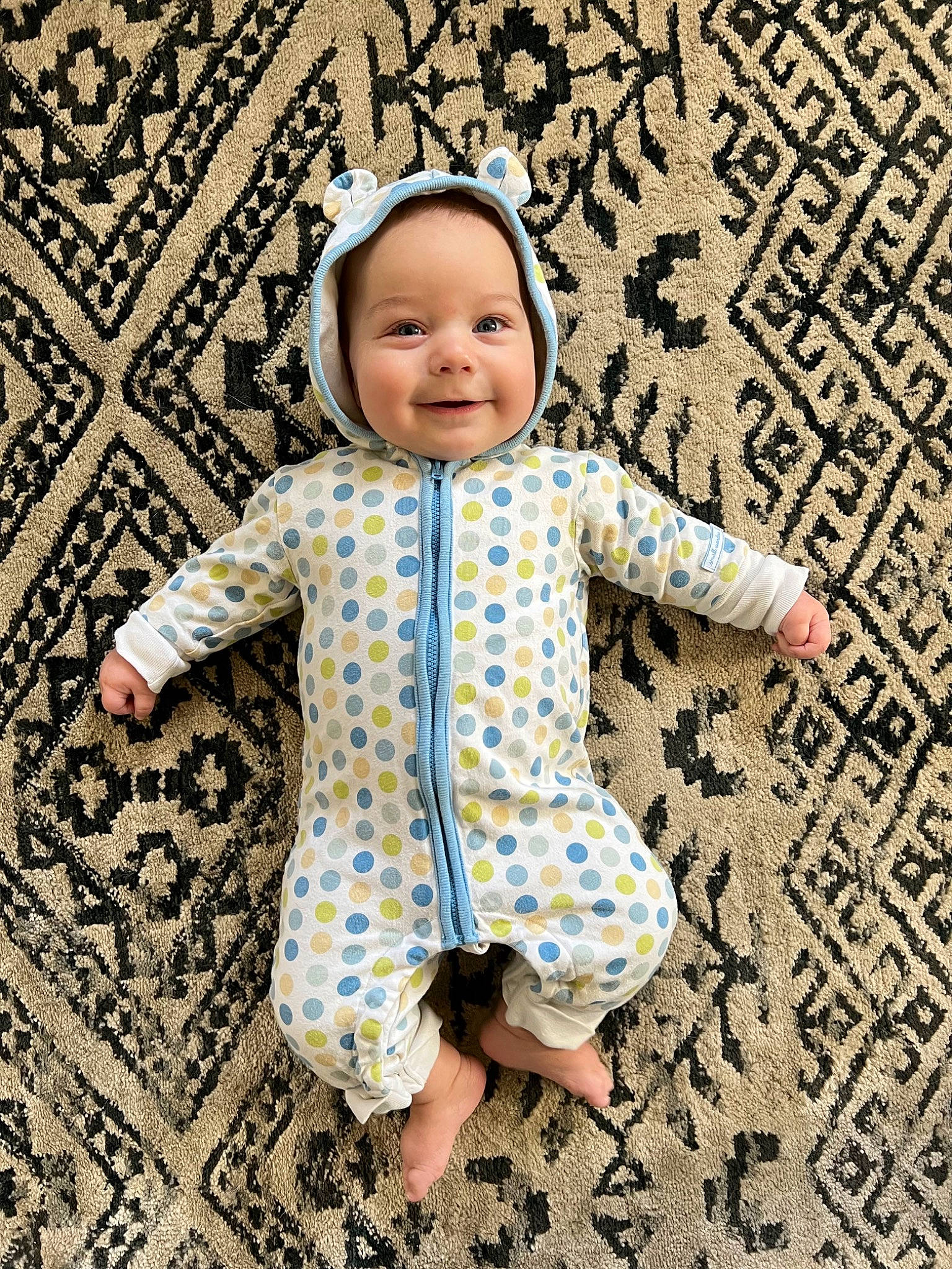 Gray is registered to the contest to win money with this photo: baby, baby_toddler_clothing, child, circle, collar, flooring, fun, gesture, happy, headwear, joy, linens, outerwear, pattern, people_in_nature, person, play, sleeve, smile, standing