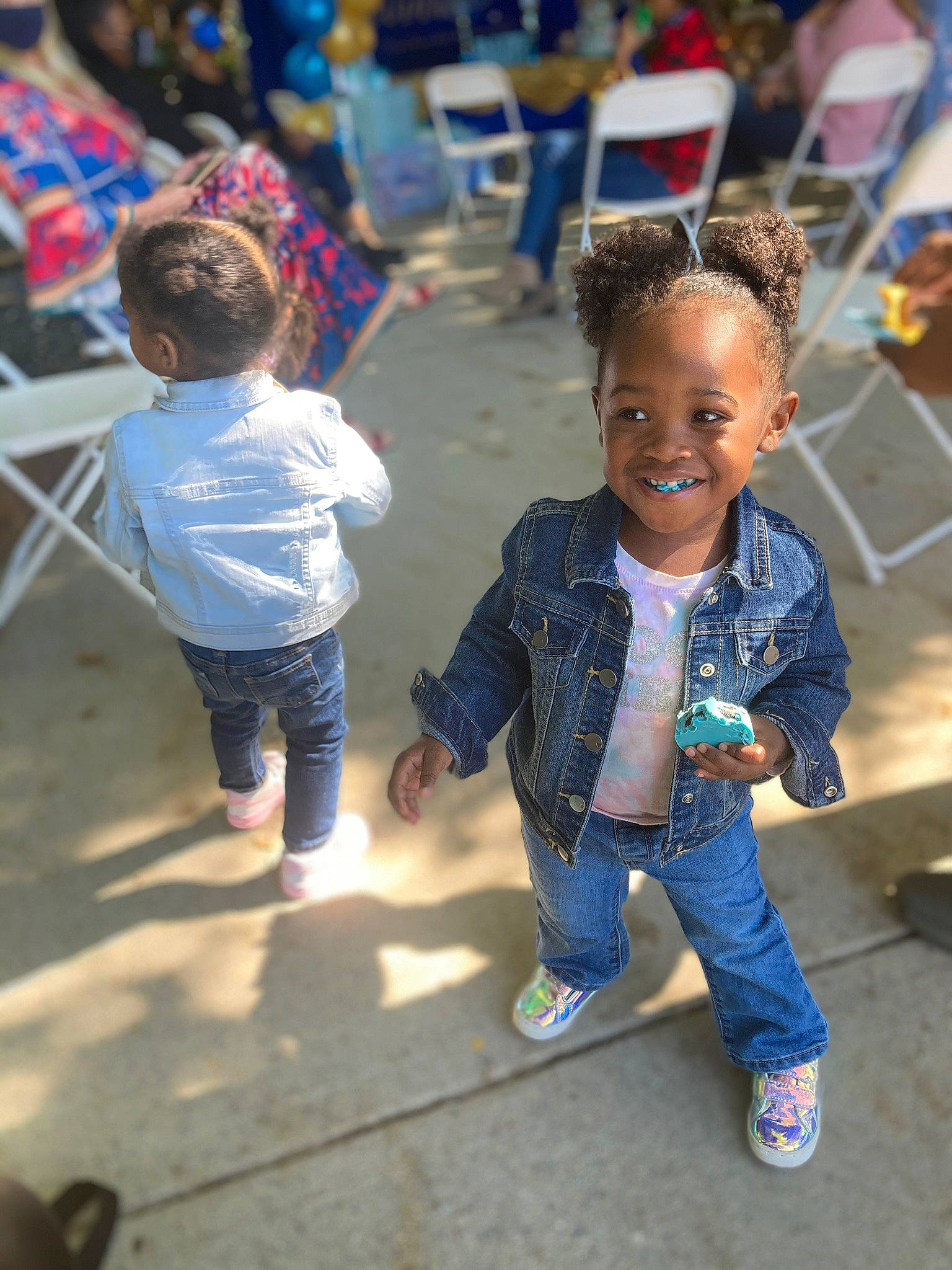 Nia is registered to the contest to win money with this photo: child, city, event, fun, hand, happy, interaction, joy, leg, leisure, pedestrian, person, recreation, sand, sitting, smile, sneakers, soil, standing, t_shirt