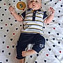 baby, infant, child, lying_down, striped_shirt, navy_pants, blanket, heart_pattern, sign, 5_months, cute, hand_gesture, curious, relaxed, indoors, portrait, young_child, clothing, foot, face