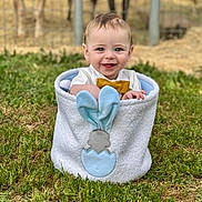 Waylyn is registered to the contest to win money with this photo: baby, child, smiling, grass, outdoor, basket, bow_tie, cute, happy, face, blue_eyes, clothing, animal_fence, nature, playful, portrait, baby_boy, greenery, soft_texture, daylight