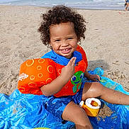 Solomon joined the competition — help win amazing prizes! toddler, beach, smile, curly_hair, orange_floaties, blue_towel, sand, ocean, waves, sunny, child, playing, toy, water, happy, summer, outdoor, vacation, sand_toy, casual_clothing
