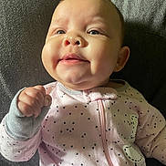 Ember is registered to the contest to win money with this photo: baby, infant, smiling, close_up, face, pink_onesie, heart_pattern, blanket, soft_texture, fist, cute, happy, young_child, portrait, indoor, child, person, sleepwear, cozy, newborn