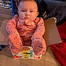 baby, child, infant, onesie, pampers_box, cardboard_box, floor, indoor, cute, face, looking, sitting, clothing, pink, patterned, footed_pajamas, bubble, curious, home, blanket