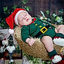 baby, sleeping, christmas, santa_hat, elf_outfit, basket, decorations, lantern, gnome, fairy_lights, holiday, festive, cozy, wood_floor, plush, greenery, red_shoes, indoors, cute, seasonal