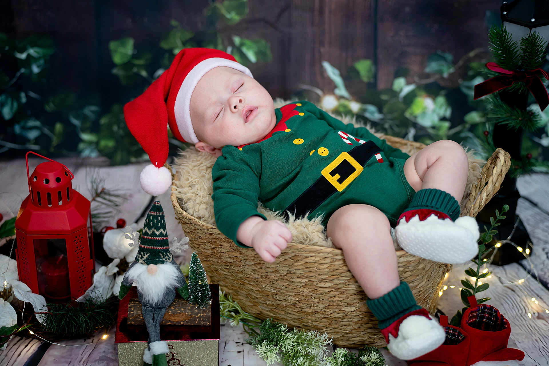 Elijah Finn joined the competition — help win amazing prizes! baby, sleeping, christmas, santa_hat, elf_outfit, basket, decorations, lantern, gnome, fairy_lights, holiday, festive, cozy, wood_floor, plush, greenery, red_shoes, indoors, cute, seasonal