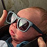 newborn, baby, infant, sunglasses, portrait, close_up, face, sleeping, clothing, jacket, blanket, adult_hand, indoor, candid, fashion, cute, head, skin, eyewear, family