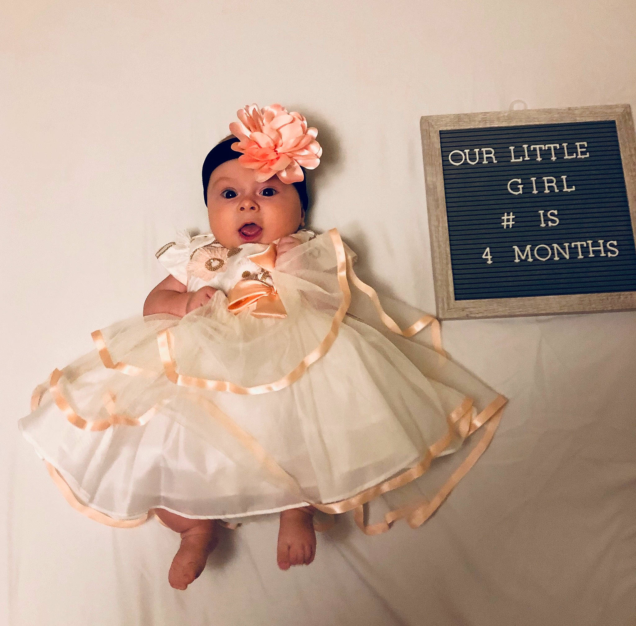 Erika is registered to the contest to win money with this photo: child, clothing, costume, doll, dress, figurine, gown, hair_accessory, headpiece, headwear, lace, outerwear, person, pink, product, ruffle, sleeve, surprise, textile, toddler