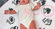 Jimma is registered to the contest to win money with this photo: baby, celebration, child, clothing, cute, footwear, gray, headband, indoors, infant, laying_down, milestone_blanket, numbers, pink, portrait, sneakers, socks, soft_surface, white, young_child