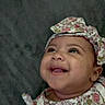 Jimma is registered to the contest to win money with this photo: apparel, baby, cheerful, child, closeup, clothing, cute, expression, face, floral_pattern, happy, headband, headwear, indoors, infant, person, portrait, skin, smiling, young