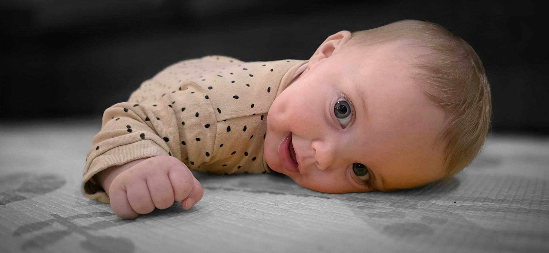 Paisley joined the competition — help win amazing prizes! baby, infant, polka_dot_clothing, lying_down, play_mat, close_up, cute, child, face, hand, soft_lighting, indoor, portrait, head, skin, expression, young, one_person, eye_contact, smile