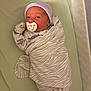Harlan is registered to the contest to win money with this photo: newborn, baby, pacifier, blanket, striped_hat, crib, mattress, sleepwear, infant, wrapped, lying_down, face, cute, small_hands, bedtime, resting, indoors, soft_lighting, child, peaceful