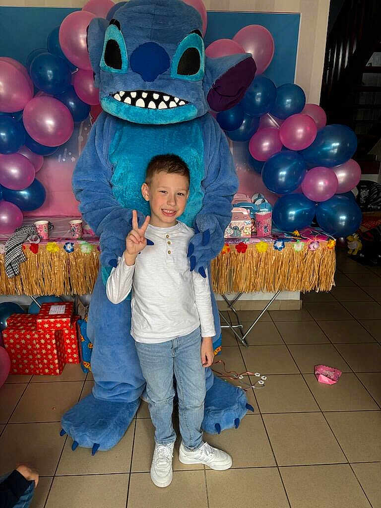 Zaïm participe au concours pour gagner de l'argent avec cette photo : child, boy, costume, stitch, balloons, party, celebration, peace_sign, smile, jeans, white_shirt, sneakers, indoor, floor_tiles, gift_boxes, table, decorations, festive, portrait, fun
